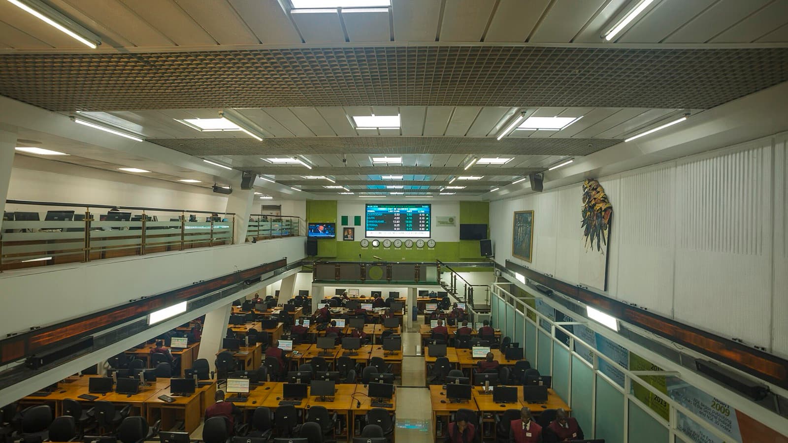 An empty stock-exchange trading floor with rows of desks and electronic market boards