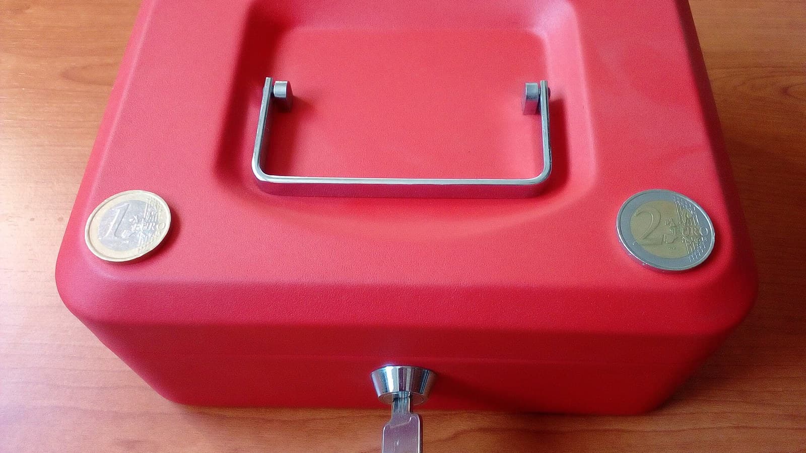Red cash lockbox with euro coins and a key, illustrating funds reserved for option assignment