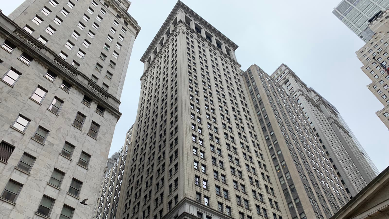 Historic office towers rise above Wall Street in Lower Manhattan on a cloudy day