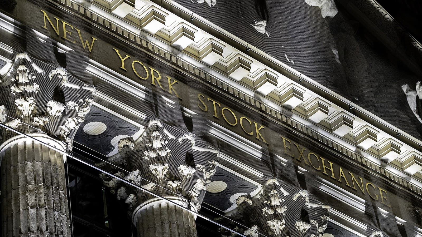 The illuminated New York Stock Exchange sign above stone columns on Broad Street
