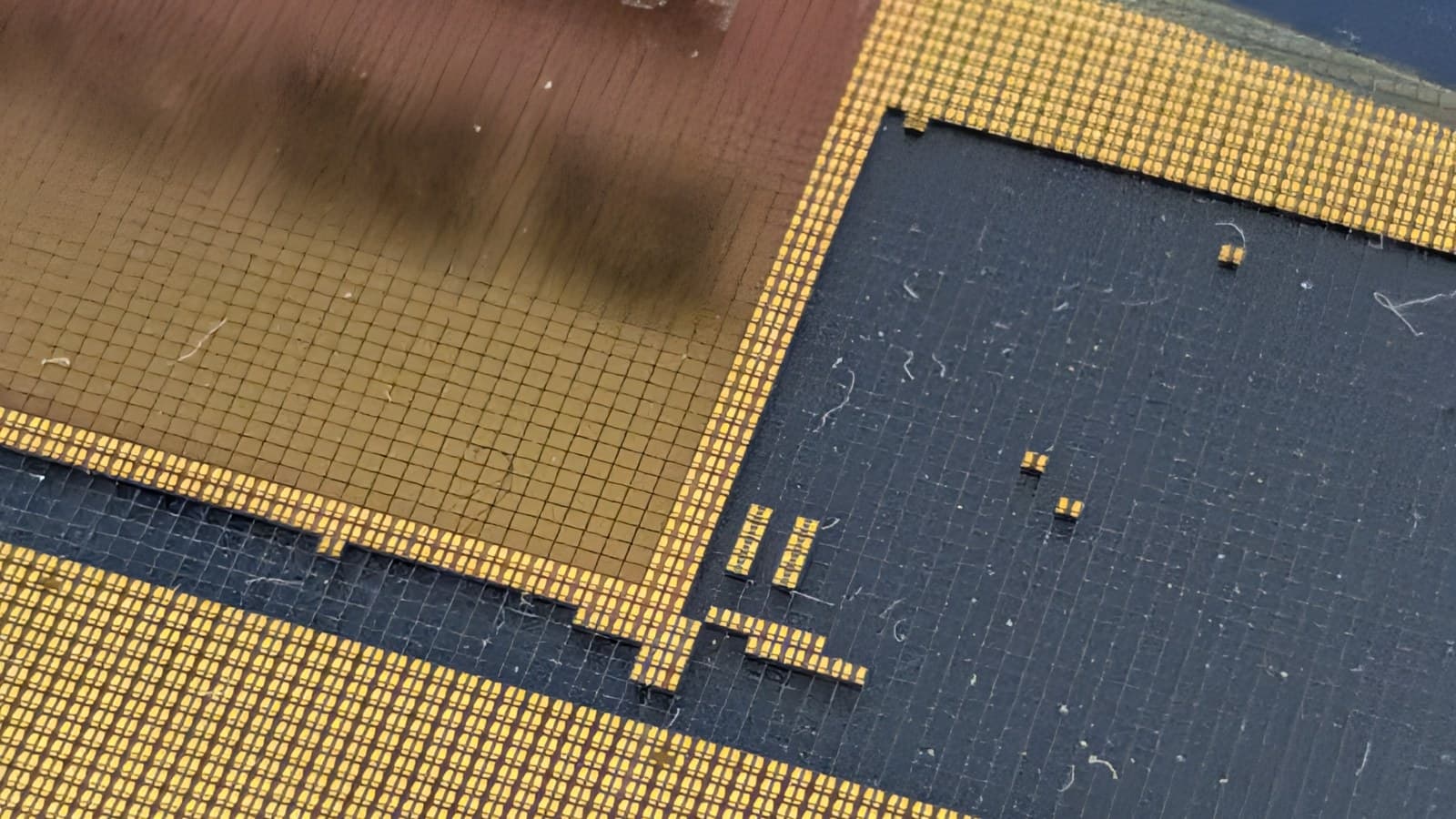 Close-up photograph of a patterned semiconductor wafer with gold-toned microchip dies