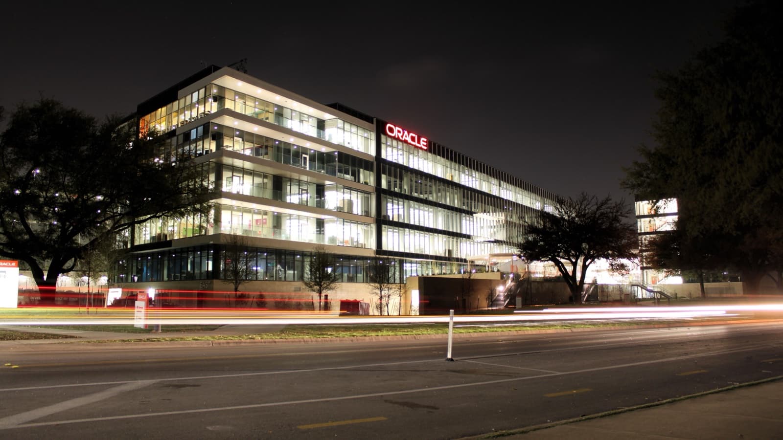 Night photograph of Oracle Riverside Campus in Austin, with illuminated offices and traffic light trails