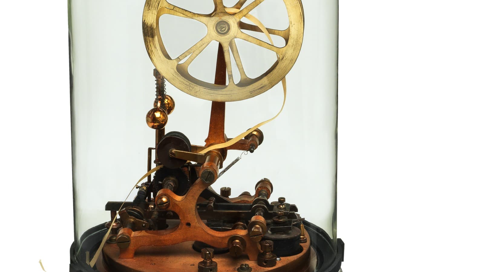 A historical stock ticker machine with paper tape and mechanical printing parts under a glass dome.