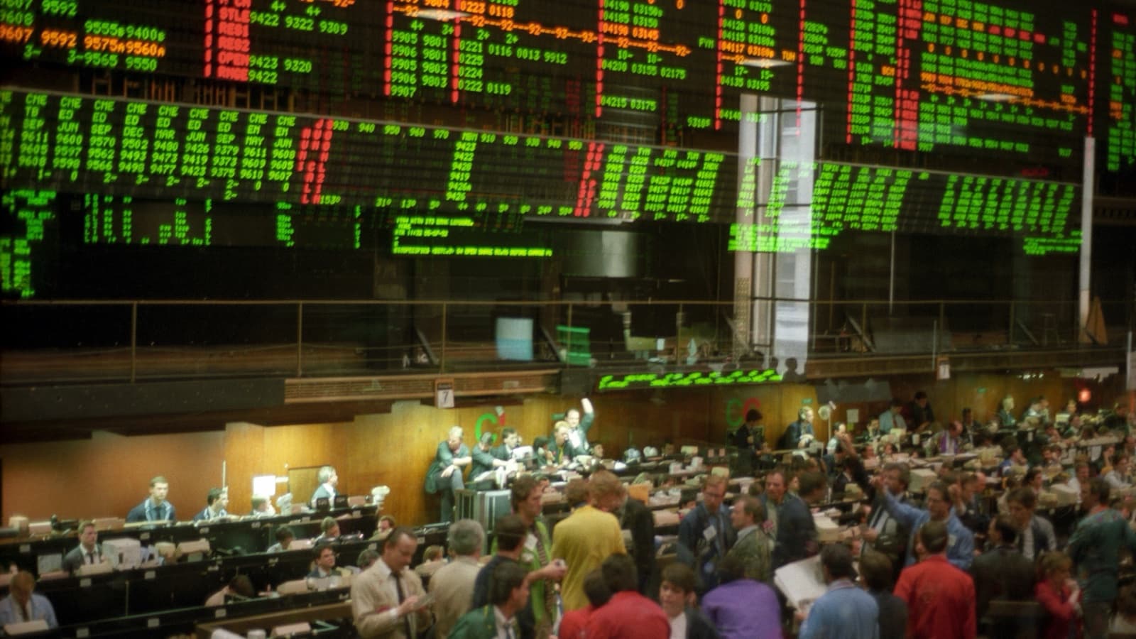 A crowded Chicago Board of Trade floor beneath red, green and orange electronic market boards