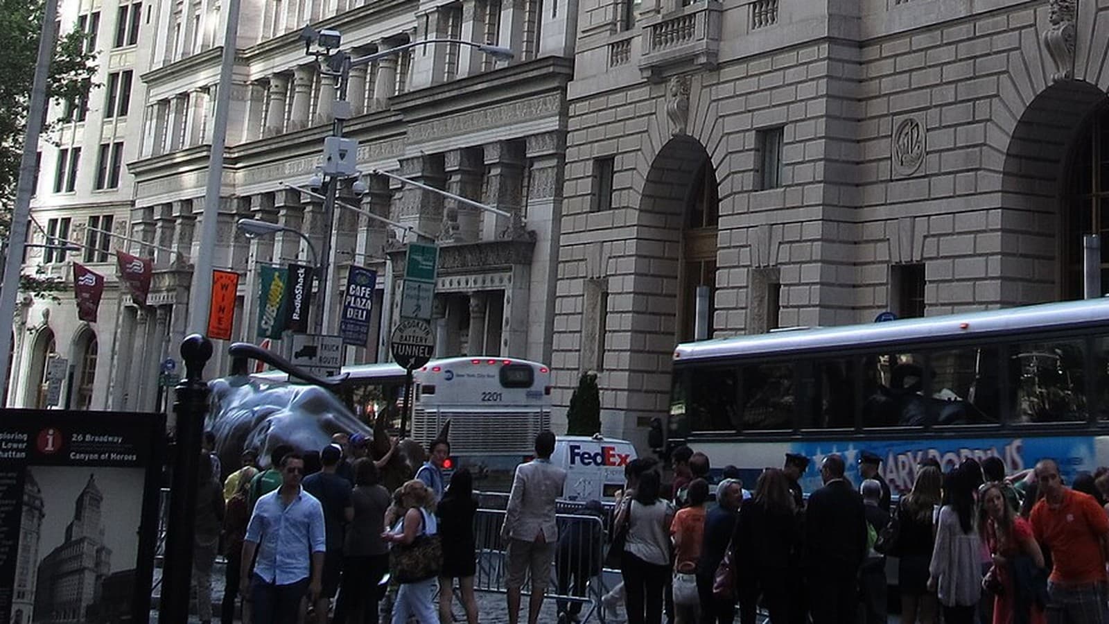 The Charging Bull surrounded by visitors in Manhattan’s financial district beneath stone market buildings