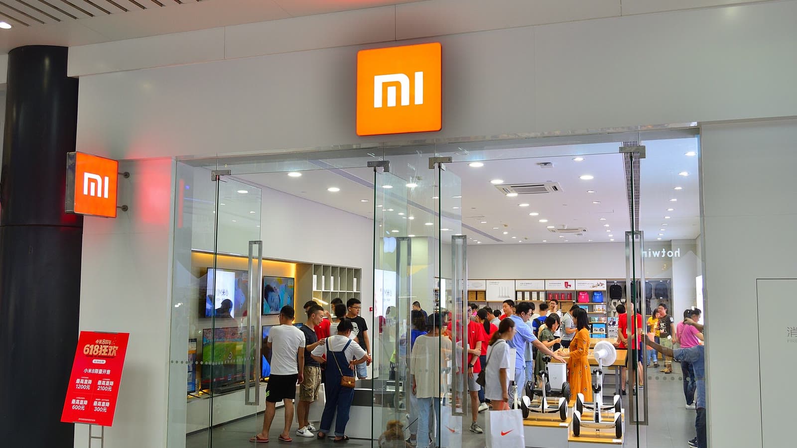 Visitors gather around smartphone displays inside a brightly lit Xiaomi store in Hangzhou