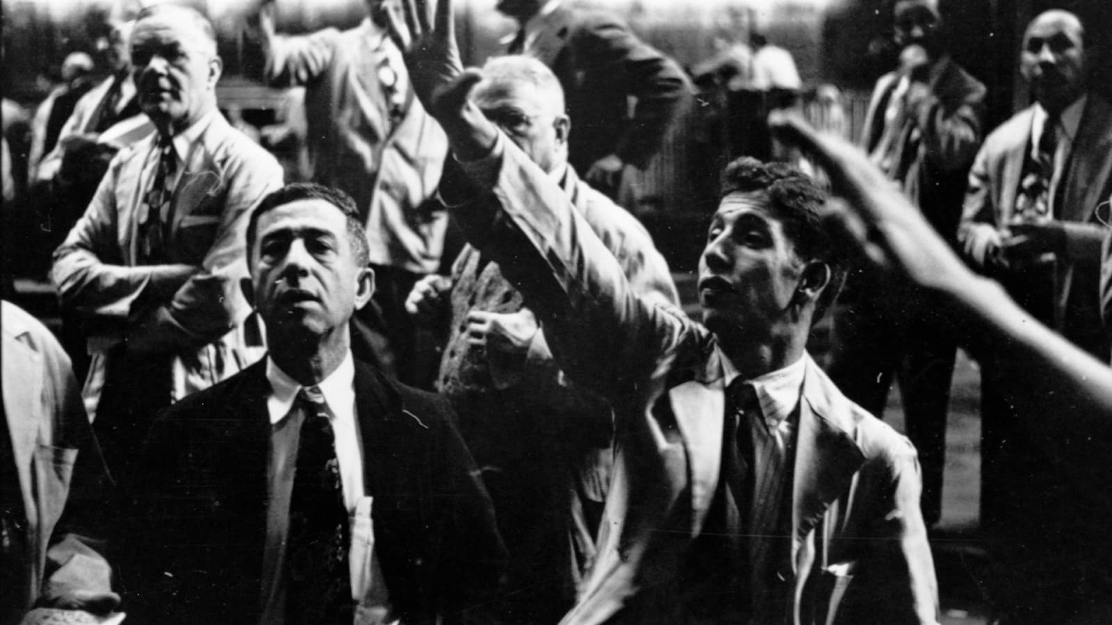 Three Chicago Board of Trade traders gesture during a crowded 1949 trading session in a black-and-white photograph