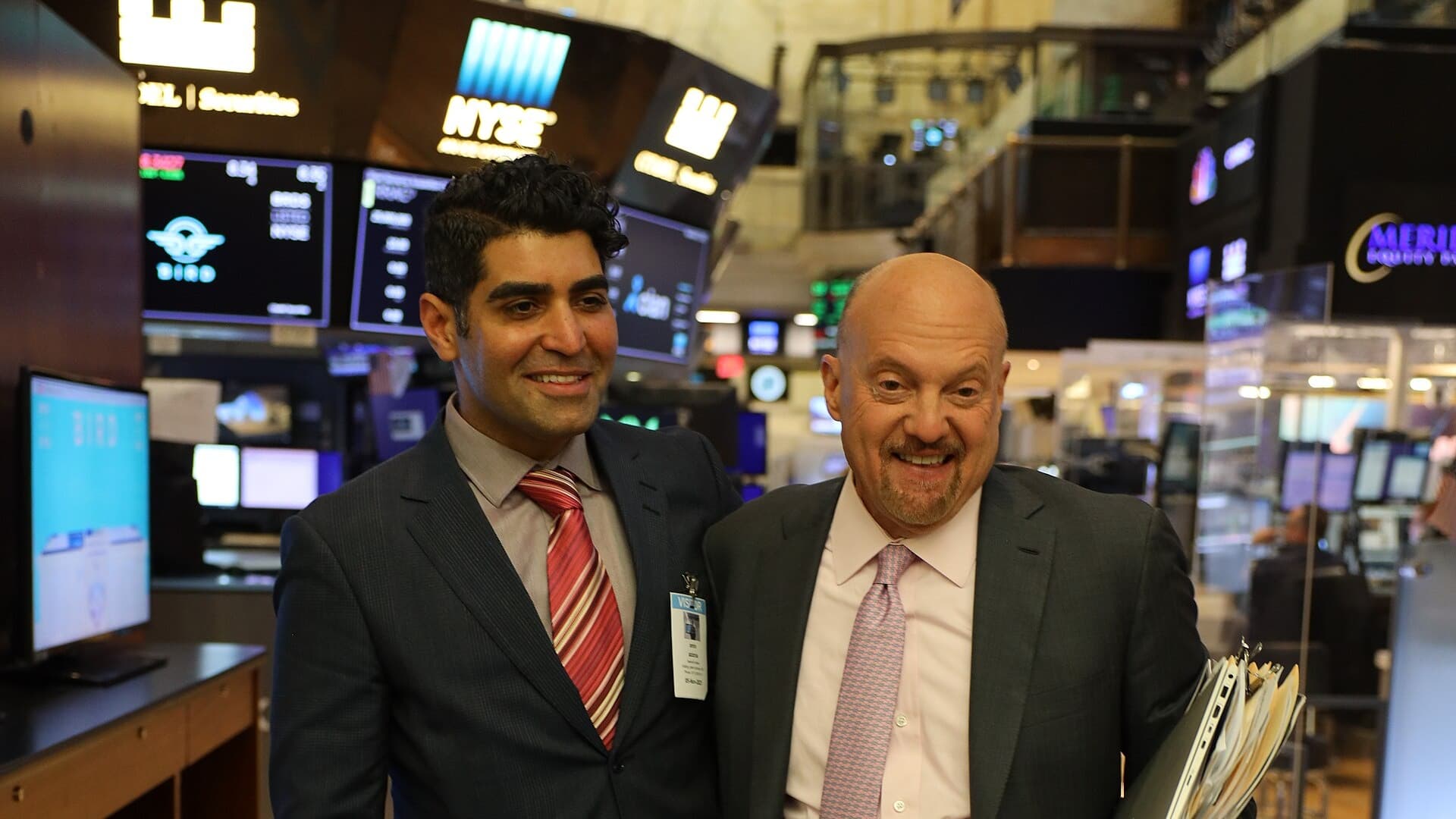 Two market professionals stand before trading screens on the New York Stock Exchange floor