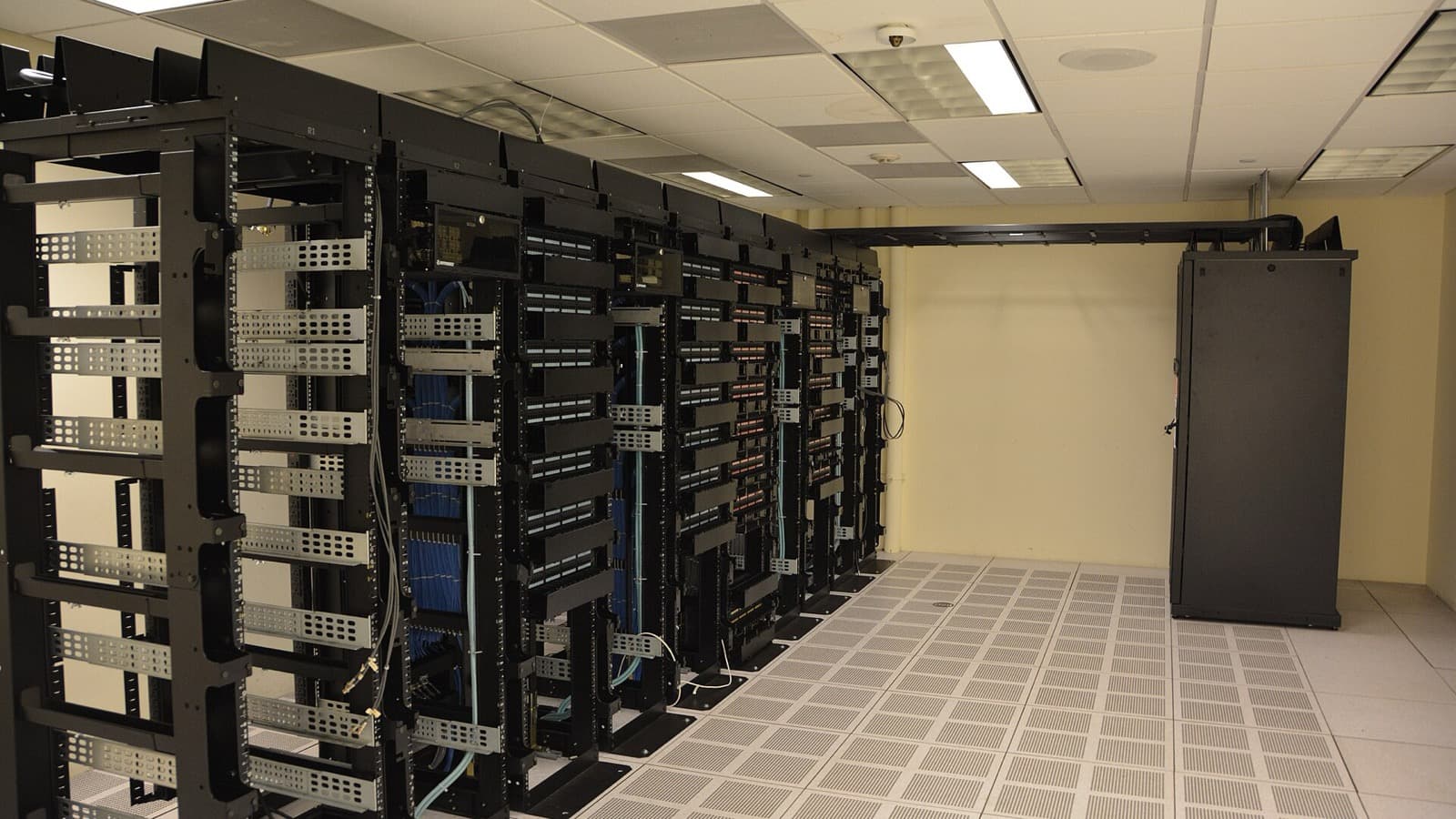 Rows of black data-center server racks in a bright equipment room