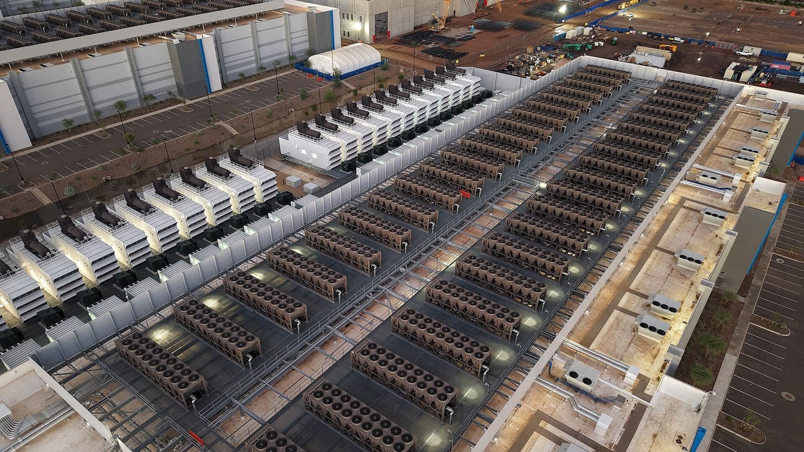 Cooling towers and backup generators on the roof of a data center under a clear sky