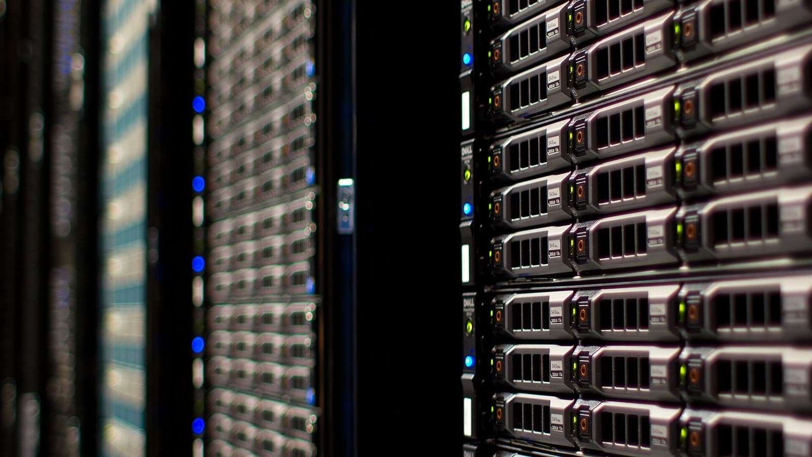 Close view down an aisle between occupied server racks in a data centre.